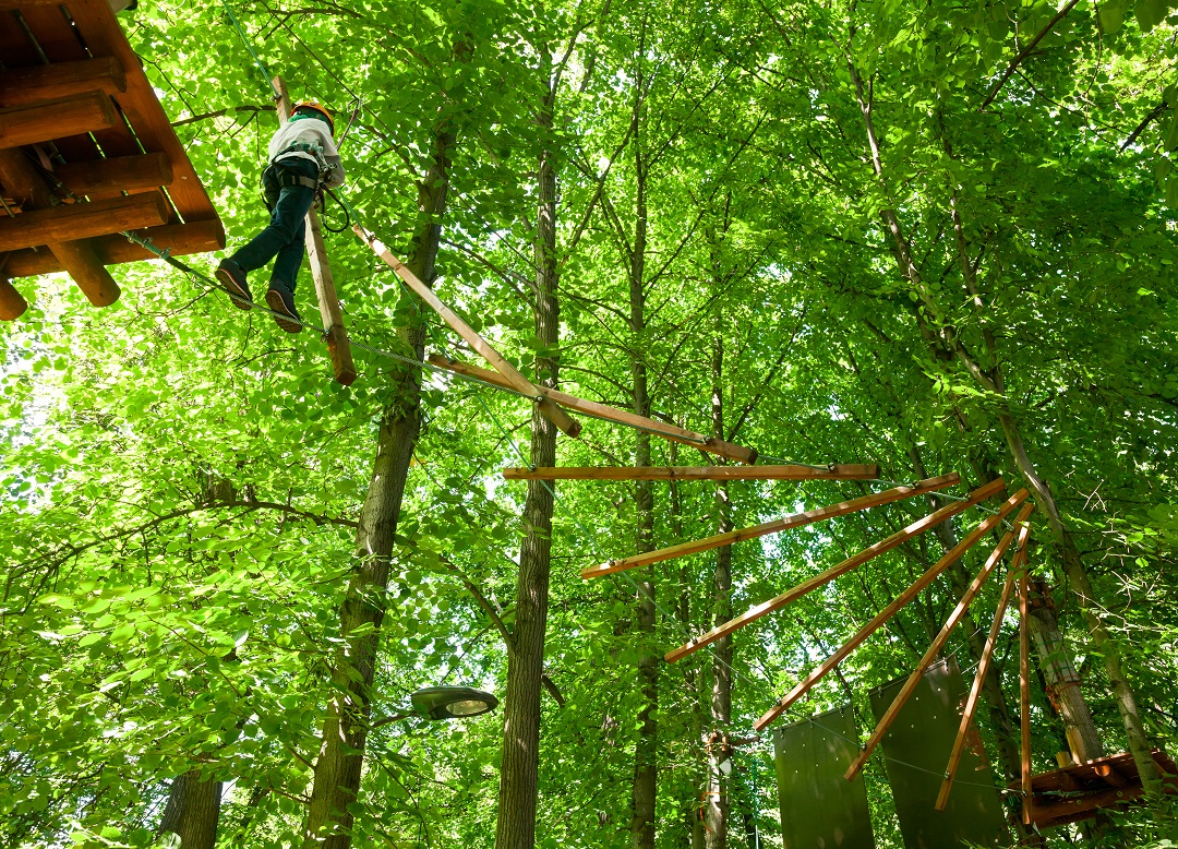 man walking on ropes course in woods